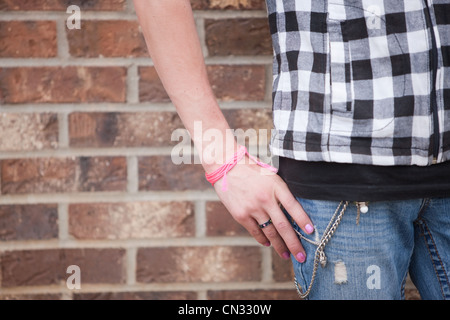 La donna vestita di nero e bianco a scacchi alto da un muro di mattoni Foto Stock