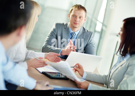 Bello leader a parlare con il suo team di giovani ed entusiasti dei lavoratori Foto Stock