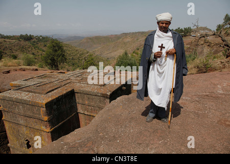 Pasqua sacerdote ortodosso tenere croce nelle antiche sunken rock-scavato nella chiesa di San Giorgio a Lalibela, Etiopia Foto Stock