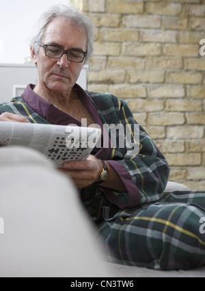 Senior uomo in rilassante in accappatoio con quotidiano Foto Stock