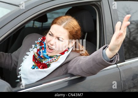 Piuttosto giovane donna caucasica agitando la sua mano e urlando seduti in auto Foto Stock