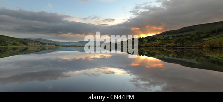 Un fuoco di autunno tramonto riflesso in acque ancora di Semer acqua, North Yorkshire. Foto Stock