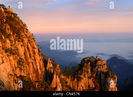 Sun red su Lion di picco e di scimmia di pietra a guardare il mare a picco prima luce con la nebbia nella vallata a huangshan gialle di montagna la Cina Foto Stock