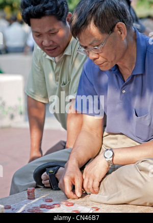 Due uomini giocare un gioco di xiangpi o scacchi cinesi con un pezzo di tessuto invece di un bordo. Foto Stock