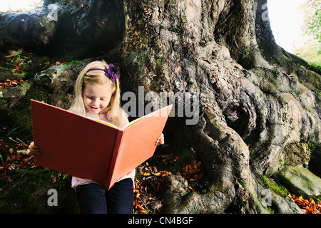 Ragazza giovane la lettura di un libro in un bosco Foto Stock