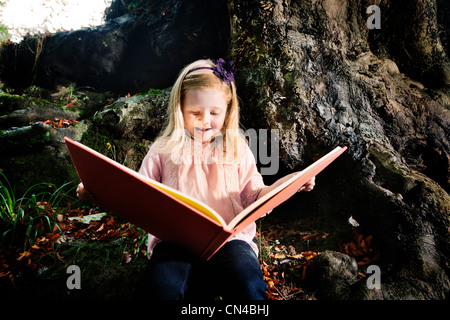 Ragazza giovane la lettura di un libro in un bosco Foto Stock