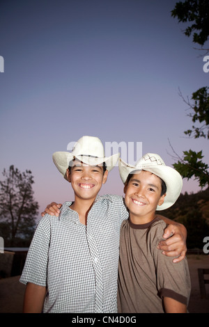 Fratelli indossare cappelli da cowboy e sorridente, ritratto Foto Stock