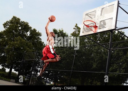Giovane uomo che saltava a Basketball hoop Foto Stock