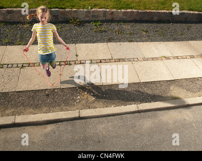 Ragazza giovane saltando sul marciapiede Foto Stock