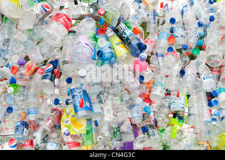 Scartare le bottiglie di plastica fissato ad una maglia di filo recinzione evidenziare la necessità di un maggiore riciclaggio di materiali preziosi Foto Stock