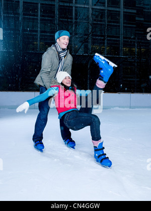 Uomo Donna di supporto come lei cade mentre pattinaggio Foto Stock