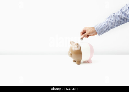 Uomo di mettere moneta nel salvadanaio Foto Stock