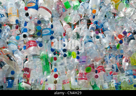 Scartare le bottiglie di plastica fissato ad una maglia di filo recinzione evidenziare la necessità di un maggiore riciclaggio di materiali preziosi Foto Stock