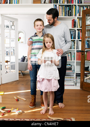 Il padre e la famiglia insieme permanente nel soggiorno, ritratto Foto Stock