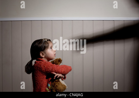 Spaventata bambina e ombra di mano adulta puntando al suo Foto Stock