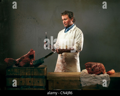 Butcher con carne di maiale, coltello di affilatura Foto Stock