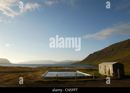 L'Islanda, Westfjords, Regione Vestfirdir, Bildudalur, piscina naturale di acqua calda, il sole di mezzanotte Foto Stock