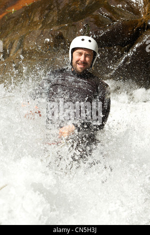 Uomo adulto scendendo in una cascata di sparare dal livello di acqua Foto Stock