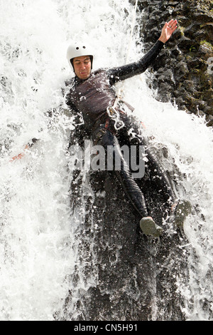 Uomo adulto scendendo in una cascata di sparare dal livello di acqua Foto Stock