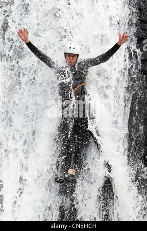 Uomo adulto scendendo in una cascata di sparare dal livello di acqua Foto Stock