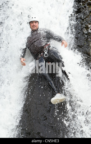 Uomo adulto scendendo in una cascata di sparare dal livello di acqua Foto Stock