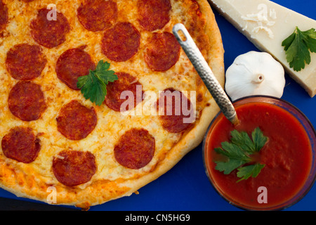 Top down shot di una salsiccia per pizza pizza con una selezione se gli ingredienti tra cui i formaggi, un spicchio di aglio e salsa di pomodoro. Foto Stock