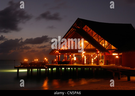 Maldive, South Male Atoll, Dhigu Island, Anantara Resort and Spa Hotel, tramonto dal mare su un ristorante su palafitte in Foto Stock