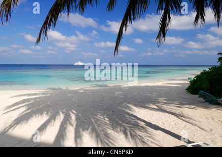 Maldive, North Male Atoll, Bandos Island, Bandos Island Resort Hotel, all'ombra delle palme sulla spiaggia e laguna Foto Stock