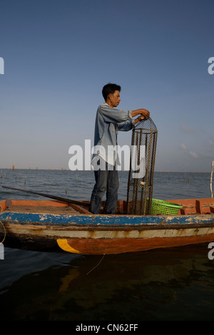 I pescatori all'alba di raccogliere le loro catture da gabbie cadere sul letto di Songkhla Lago. Foto Stock