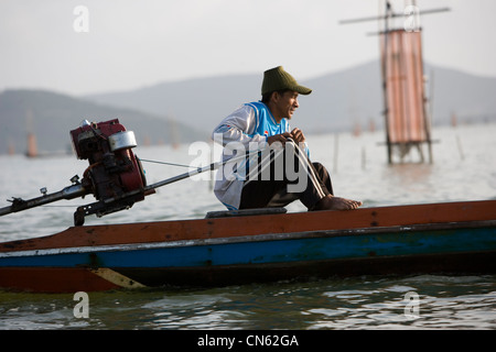 I pescatori all'alba di raccogliere le loro catture da gabbie cadere sul letto di Songkhla Lago. Foto Stock
