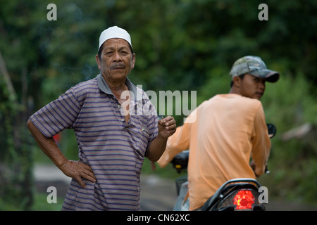 Un pescatore fuma la sua sigaretta in un villaggio di pescatori sulle sponde del lago di Songkla, Thailandia Foto Stock