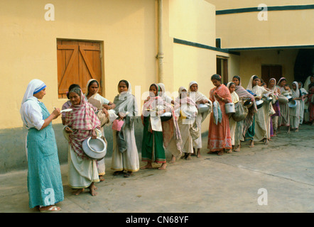 Le donne che trasportano pentole in inizio di mattina di coda di alimentare a Madre Teresa ha la missione di Calcutta, in India Foto Stock