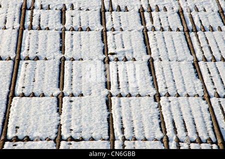 Sullo sfondo di un tetto in ardesia coperte di neve in inverno il sole illumina. Materiale pericoloso per la salute. Foto Stock