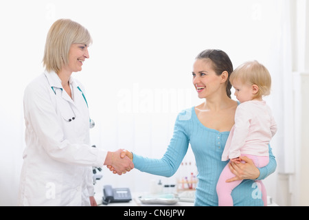 Grato mom agitando la mano per la mezza età medico pediatrico Foto Stock