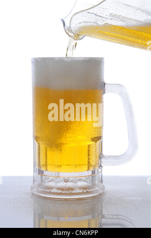 Primo piano di un boccale di birra su un wet bar contatore essendo riempita da un pour da una brocca. Foto Stock