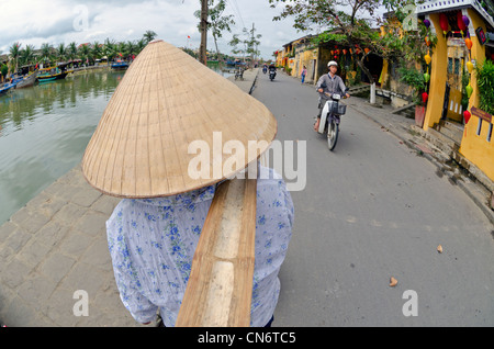 Donna della forcella di trasporto cesti di frutta in street, Hoi An, Vietnam Foto Stock