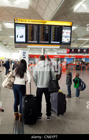 Le persone che ricercano le informazioni di volo pensione al momento del check in, l'aeroporto di Stansted Essex REGNO UNITO Foto Stock