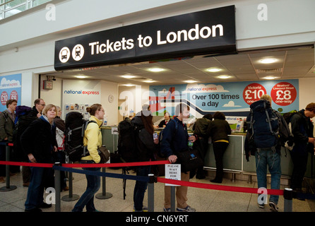 Aria i viaggiatori che arrivano all'aeroporto di Stansted coda per i biglietti per Londra Stansted Aeroporto Essex REGNO UNITO Foto Stock