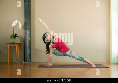 Donna nella sua 40's praticare lo yoga pone laterale ad angolo; Utthita Parsvakonasana. Foto Stock