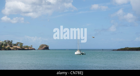 Uno yacht ormeggiato al largo di Castries con un piano distante lasciando la pista di George F.L. Dall'aeroporto di Charles, Santa Lucia Foto Stock