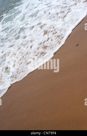 Primo piano dettaglio della schiuma onde del mare il lavaggio a terra presso la spiaggia. Foto Stock