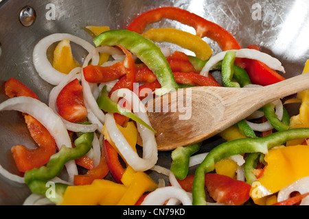 Primo piano di fettine di peperoni e cipolle essendo agitare fritto in un acciaio inossidabile wok pan. Foto Stock