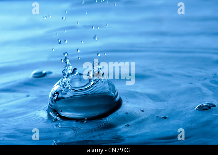 Un blu acqua texture di sfondo e splash con goccioline formando una corona di forma. Profondità di campo. Foto Stock