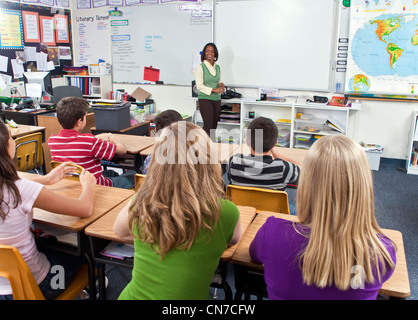 11-13 anno Olds multi multiculturale culturale etnicamente diversi multi etnico razziale scrivanie degli studenti ascolta African American femaleTeacher lezione Foto Stock