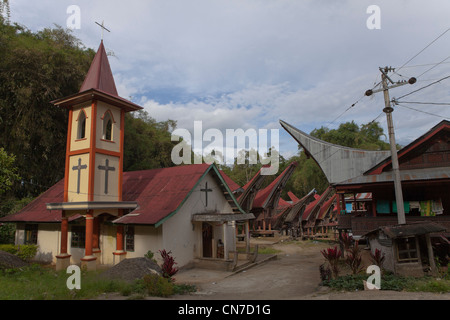 La chiesa e le case di un villaggio tradizionale di Tana Toraja. Rantepao, Sulawesi, Indonesia, Pacifico Asia del Sud. Foto Stock