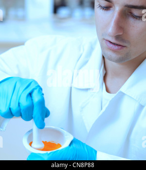 Ritratto di un giovane ricercatore maschio utilizzando un mortaio e un pestello per omogeneizzare la miscela mentre si lavora in un laboratorio Foto Stock