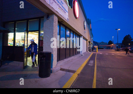 Shopper femmina lasciando un Safeway fruttivendolo al crepuscolo, Salida, Colorado, STATI UNITI D'AMERICA Foto Stock