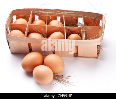 Uova con una cannuccia in un cestello di legno su uno sfondo bianco. Foto Stock