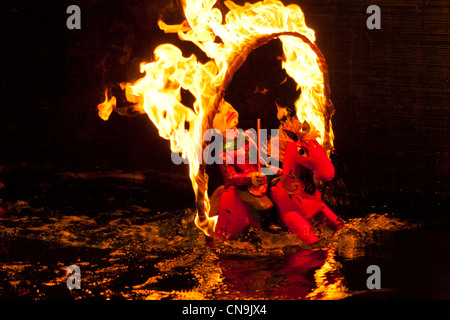 Fantoccio acqua, uomo su passeggiate a cavallo attraverso le fiamme Thang Long acqua Puppet Theatre, Hanoi, Vietnam Foto Stock