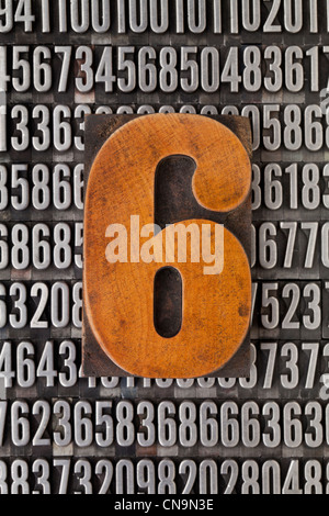 Numero sei nella stampa tipografica vintage tipo legno sullo sfondo casuale di numeri di metallo Foto Stock